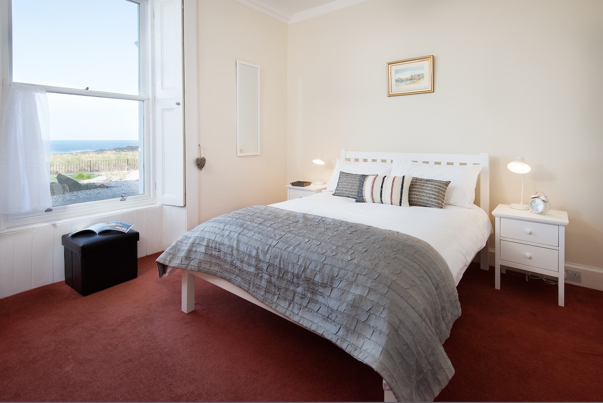 East Bay Beach House - bedroom one with double bed, side table and sea views