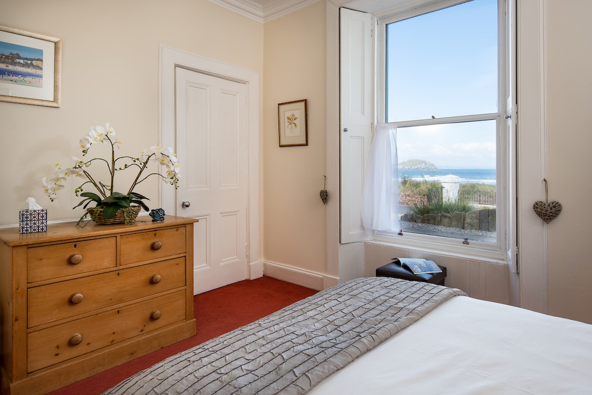 East Bay Beach House - bedroom one with double bed, chest of drawers and sea views