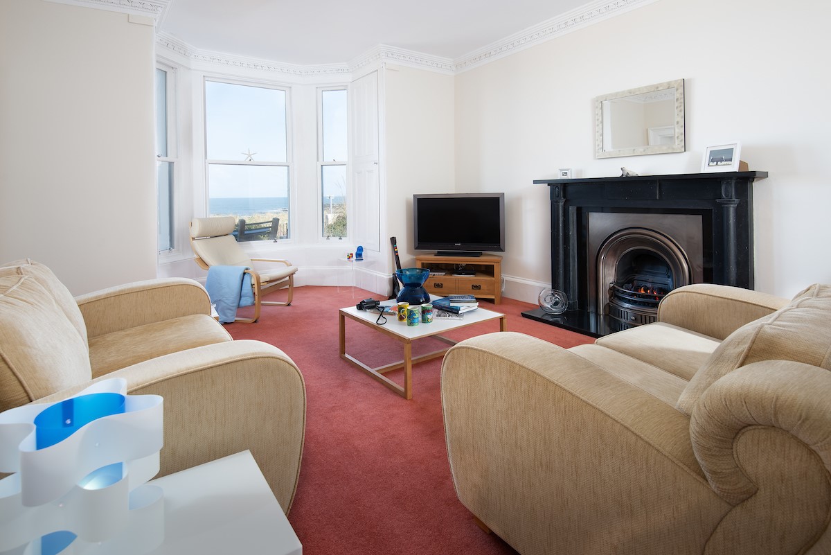 East Bay Beach House - TV room/play room with gas fire, TV, sofas and large bay window with sea views