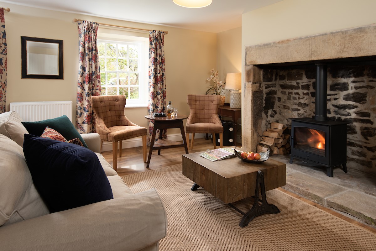Aydon Castle Cottage - sitting room with wood burning stove and stone inglenook fireplace