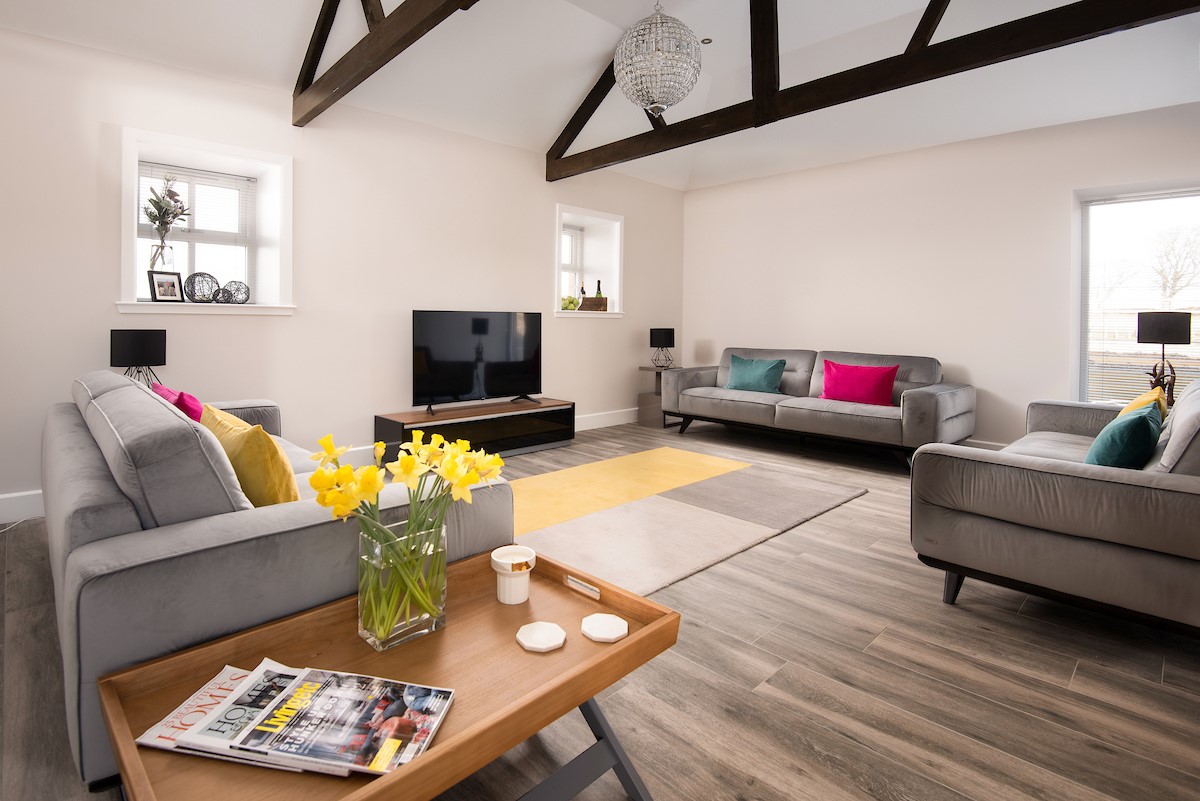 The Steading at West Lyham - sitting room with three large sofas, large TV and pops of colour