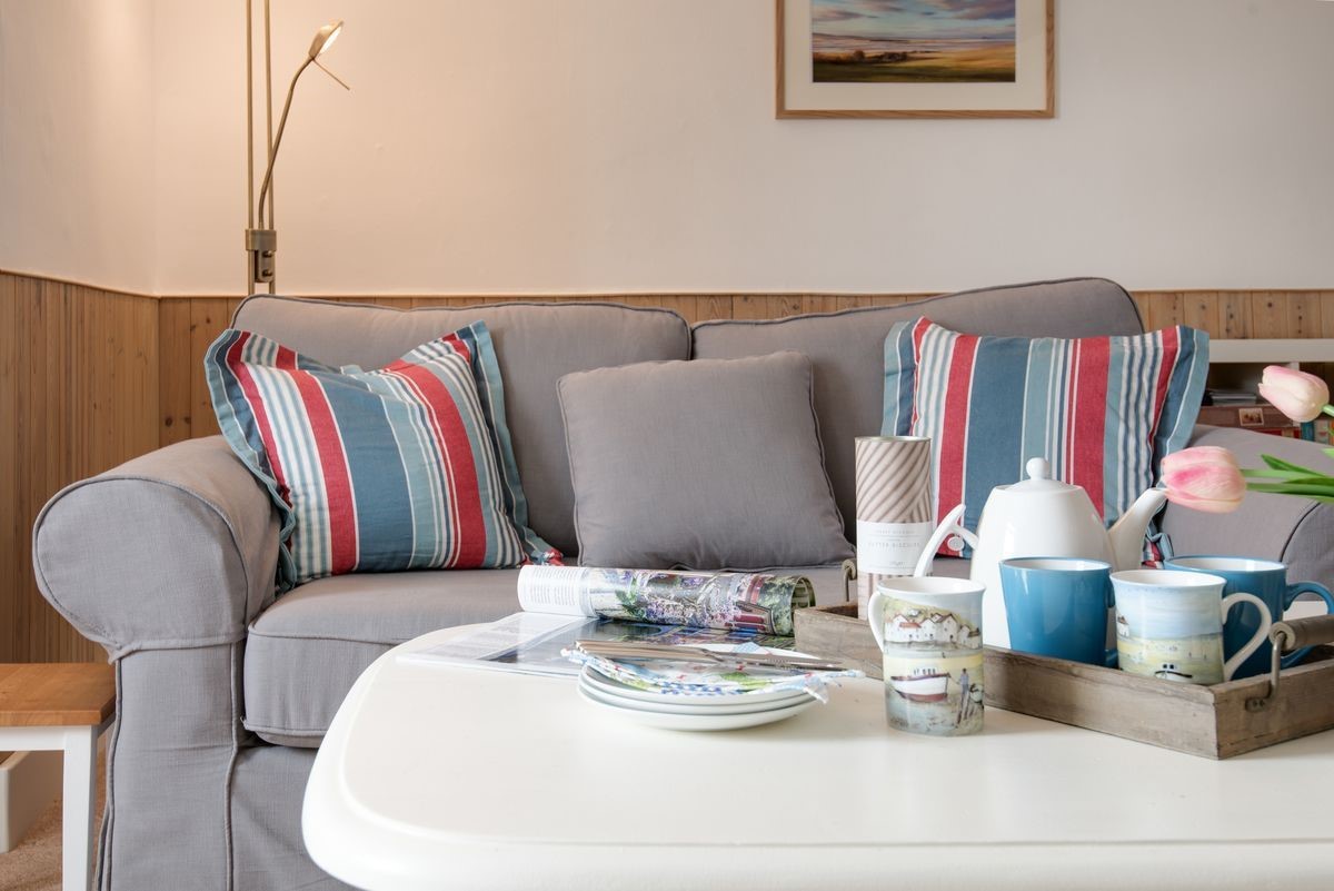 Beachcomber Cottage - the sofa in the sitting room with coastal themed striped cushions