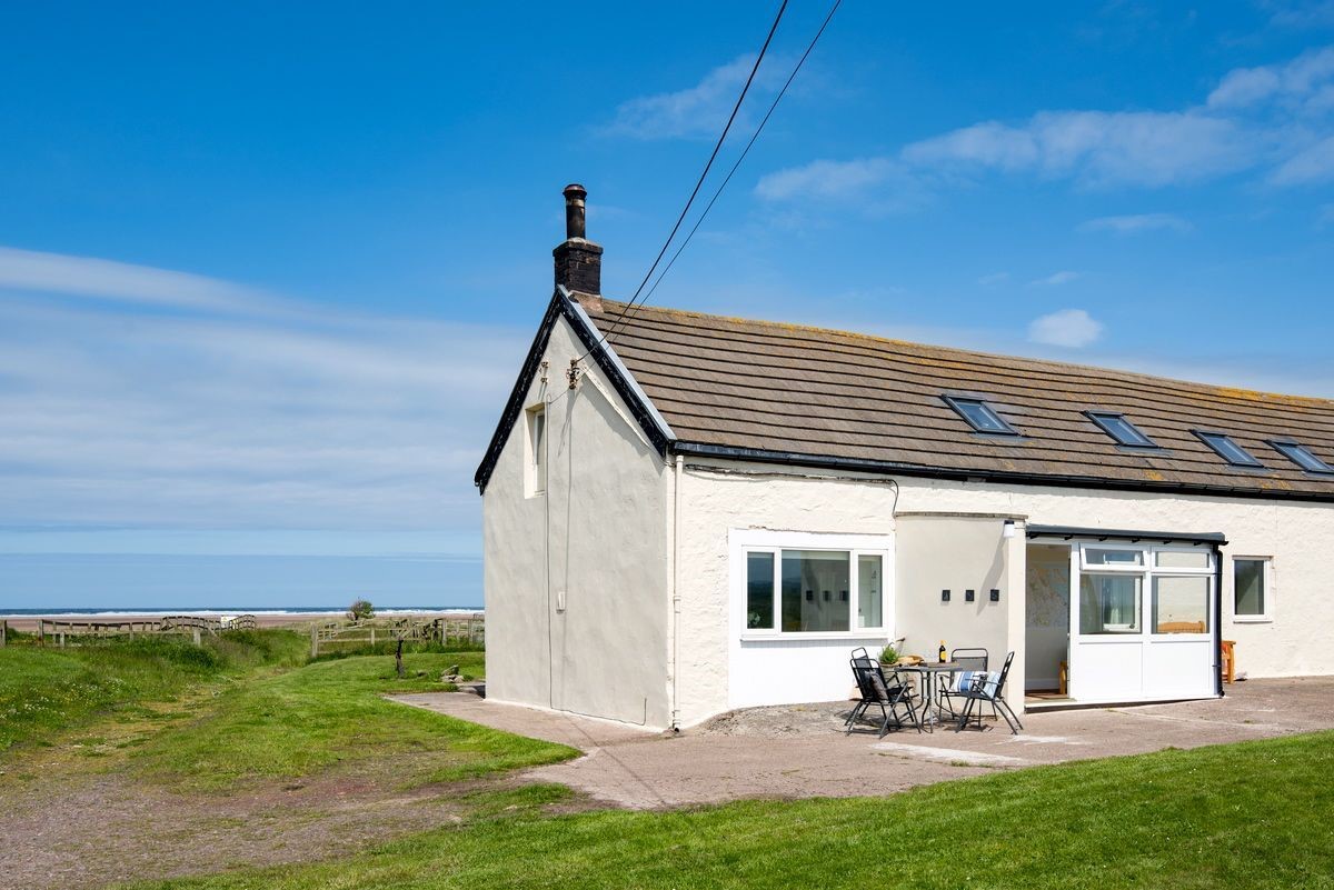 Beachcomber Cottage - the exterior of the cottage with access door and Goswick beach in the background
