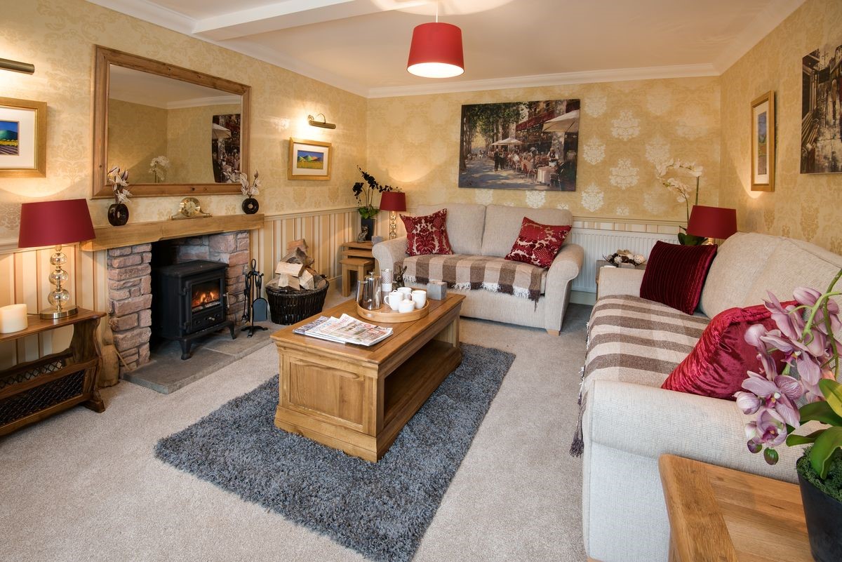Dryburgh Stirling One - sitting room with sofas, wood burning stove, coffee table and red accents
