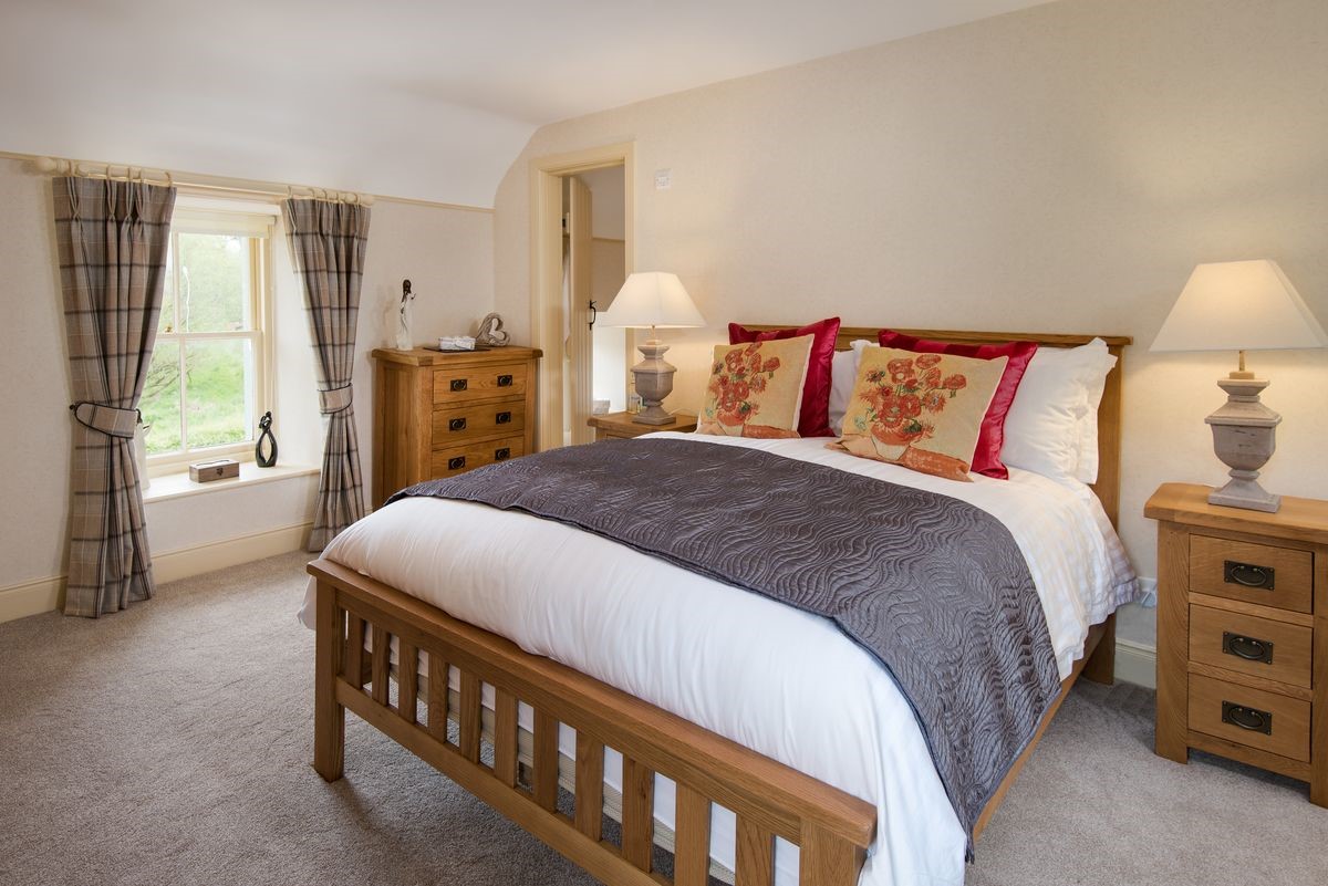 Dryburgh Stirling One - bedroom one with double bed, side tables, chest of drawers and en suite bathroom
