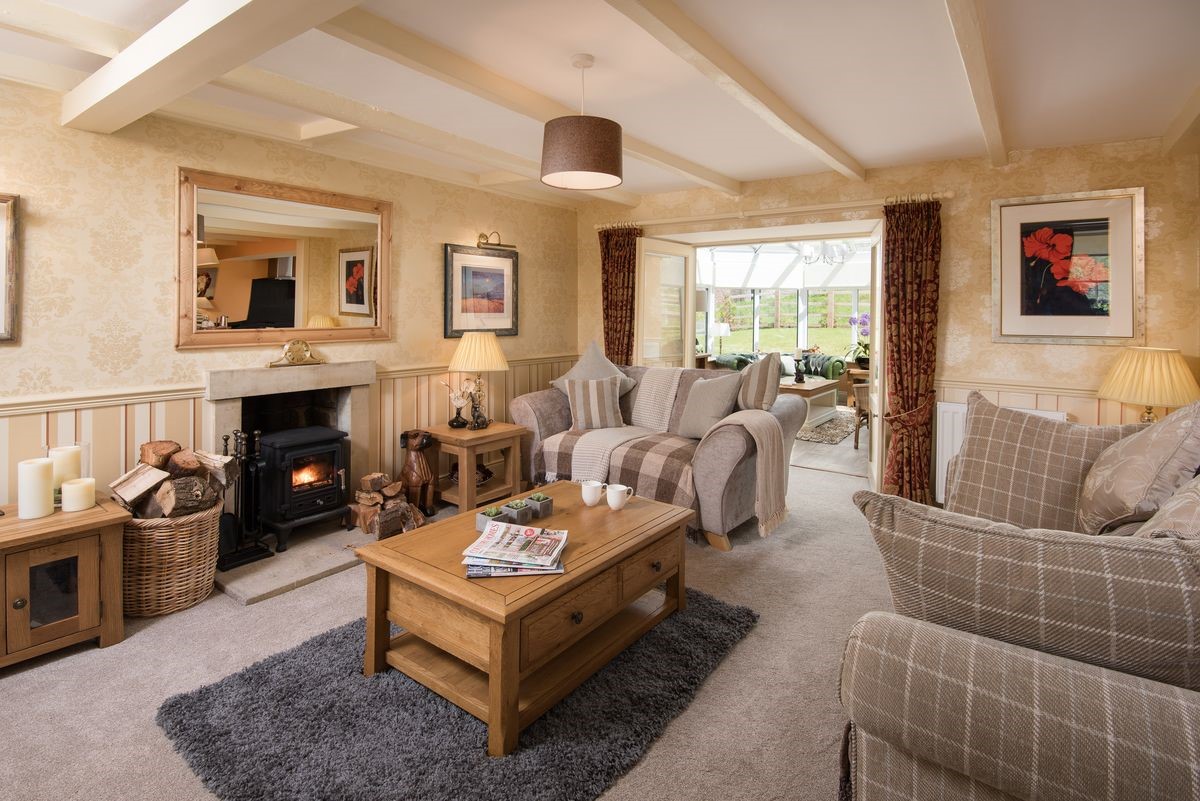 Dryburgh Stirling Two - sitting room with wood burning stove and doors leading into the conservatory