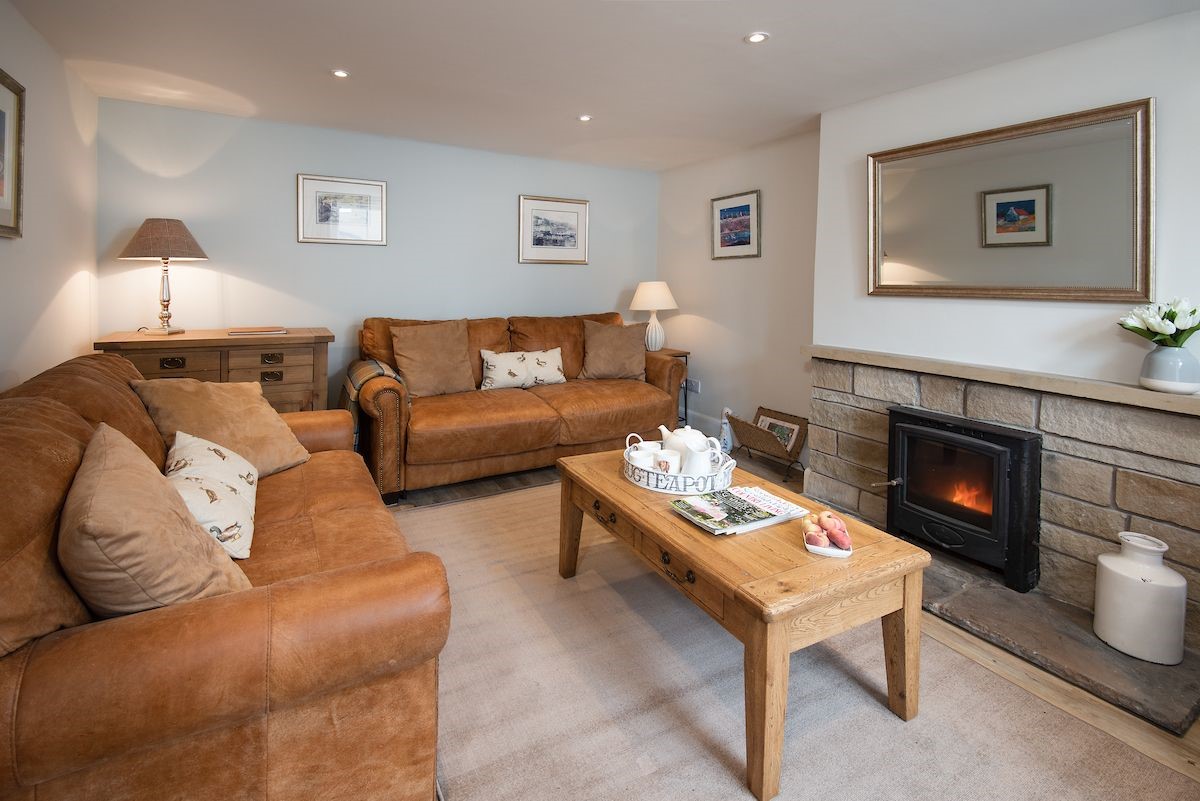 Crosslea - sitting room with two large sofas, multi-fuel stove and chest of drawers