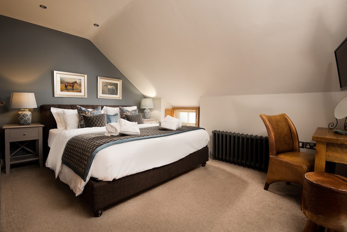 Coach House - bedroom three on first floor with super king bed, bedside tables and dressing table
