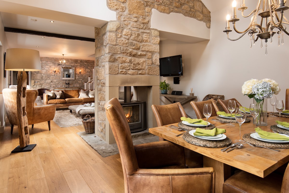 Coach House - dining area with seating for eight guests leading through to the sitting room with wood burning stove