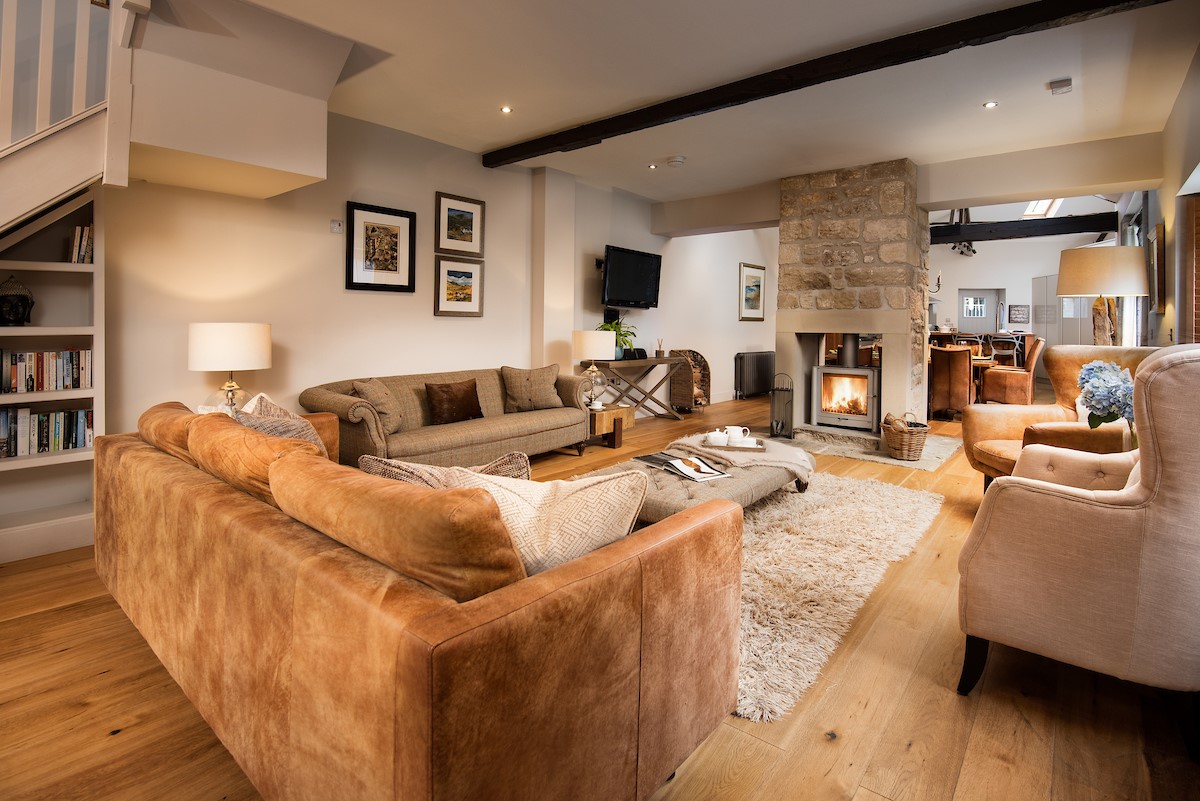 Coach House - open-plan sitting room with large sofas, armchairs and wood burning stove