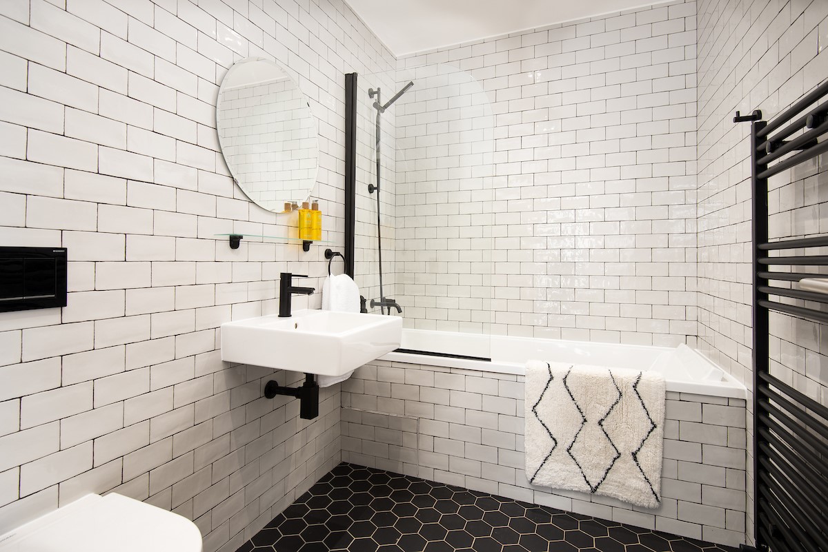 6 The Bay, Coldingham - family bathroom featuring a bath with shower over and stylish monochrome design
