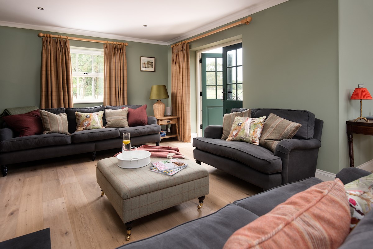 Risingham Cottage - sitting room with patio doors leading outside