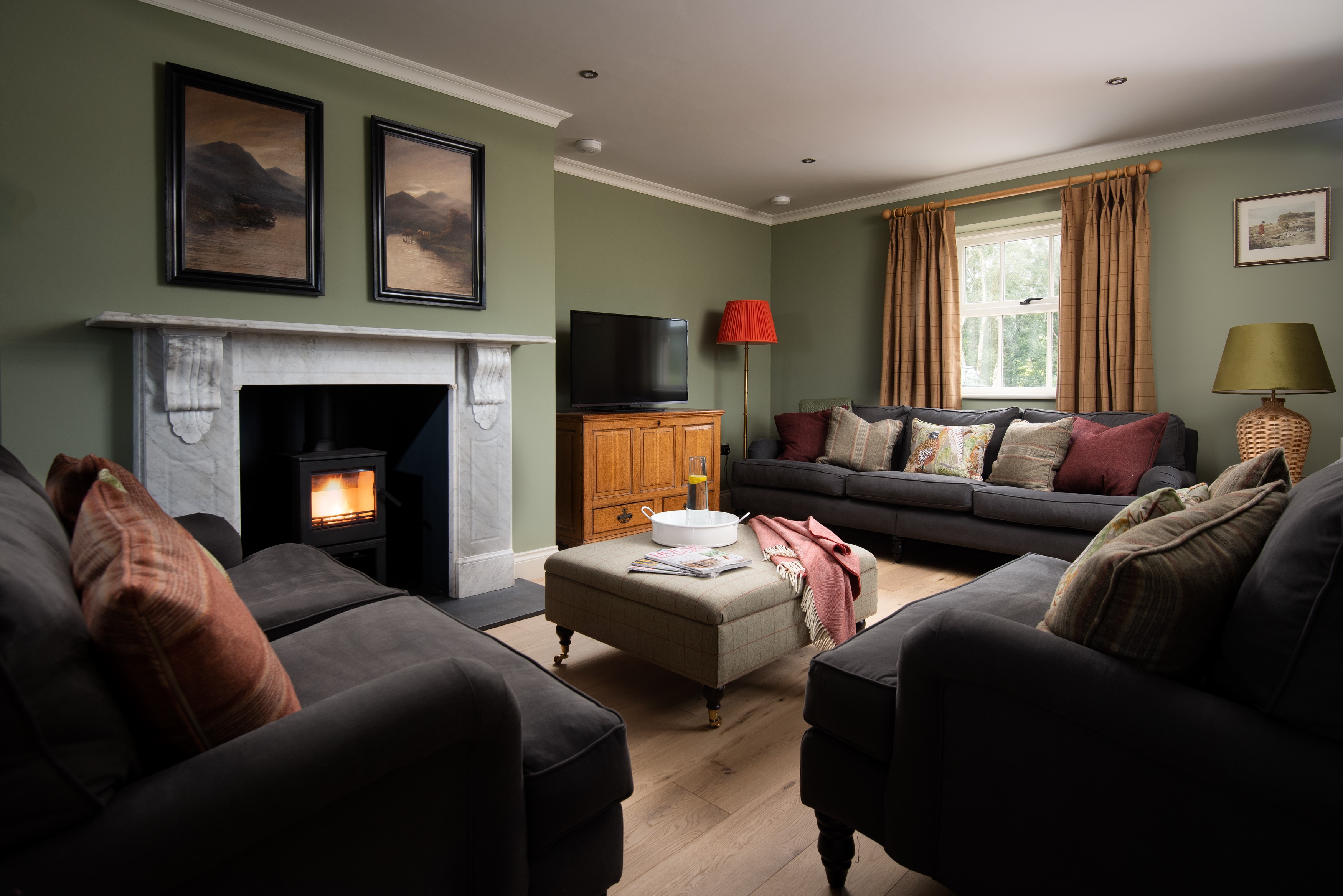 Risingham Cottage - sitting room with comfortable seating in front of a log burner