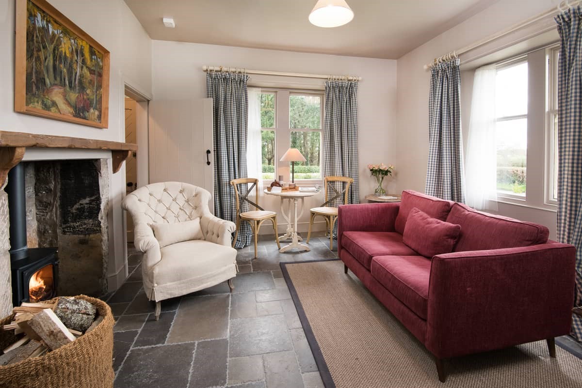 Park End - airy sitting room with sofa for two and single armchair in front of the wood burner
