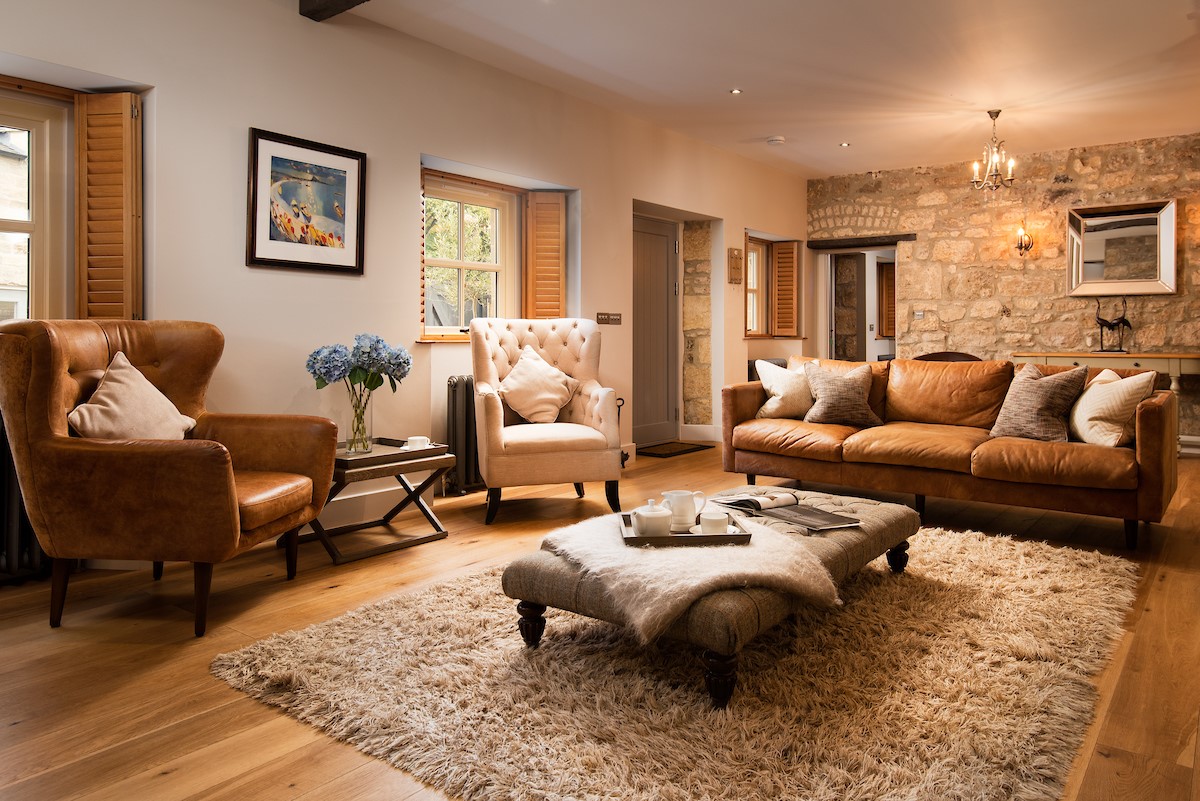 Coach House - sitting room with armchairs, sofa and door leading into the courtyard