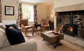 Aydon Castle Cottage - sitting room with wood burning stove and stone inglenook fireplace
