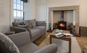 Chaffinch Cottage - sitting room with sofa, armchair and coffee table by the wood burning stove