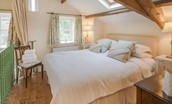 East Cottage - bedroom one with king size bed, side tables and beamed ceilings overlooking the sitting room