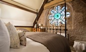 Lindisfarne View - bedroom two with cast iron bedstead and stunning stained glass window detailing - please note as per the descriptor the bath is no longer in place, updated photos coming soon