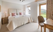 Granary - bedroom four on the lower ground floor with zip and link beds, dressing table and door to garden