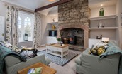 Curlew Cottage - sitting room with stone inglenook fireplace, wood burning stove, TV and sofas