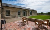 Beeswing - the patio and lawned garden and the exterior of the house with arched windows