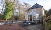 The Old Paper Mill - pretty conservatory and courtyard garden surrounded by peaceful woodland